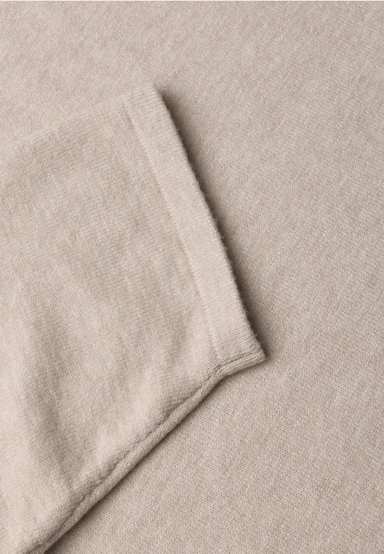 Nahaufnahme eines beigen Stoffes mit eingenähter Tasche.