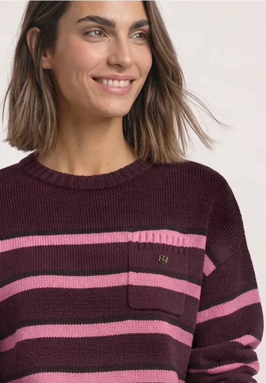 Lächelnde Frau in gestreiftem Strickpullover (pink und lila) von Schulter bis Brust.