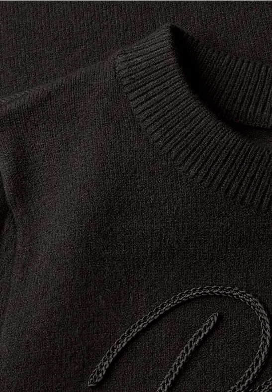 Nahaufnahme eines schwarzen Strickpullovers mit dezentem, eingearbeitetem Logo-Detail.