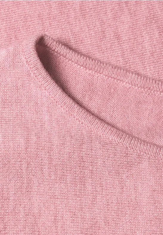 Nahaufnahme eines rosa Strickpullovers mit texturierter Oberfläche und Rundhalsausschnitt.