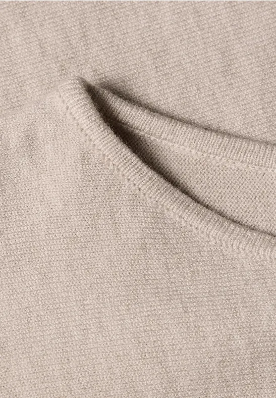 Close-up van beige gebreide stof met een gestikte rand.