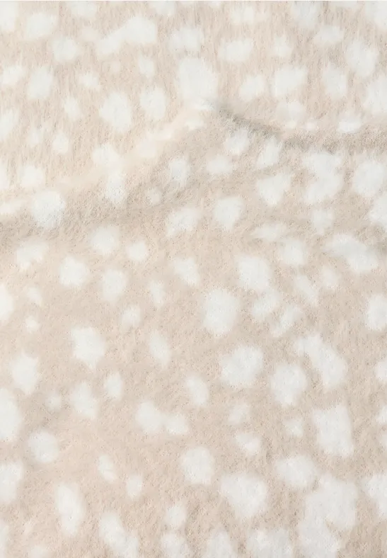 Naheinstellung einer flauschigen, beigefarbenen Oberfläche mit weißen Punkten.