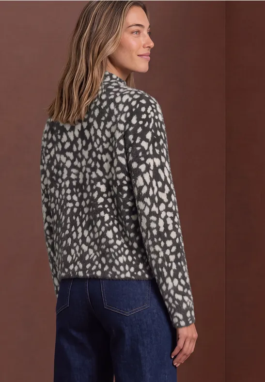Frau in gemusterter schwarz-weißer Jacke und Jeans, von hinten fotografiert.