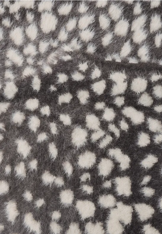 Flauschiges Fell mit unregelmäßigen weißen Tupfen auf grauem Hintergrund