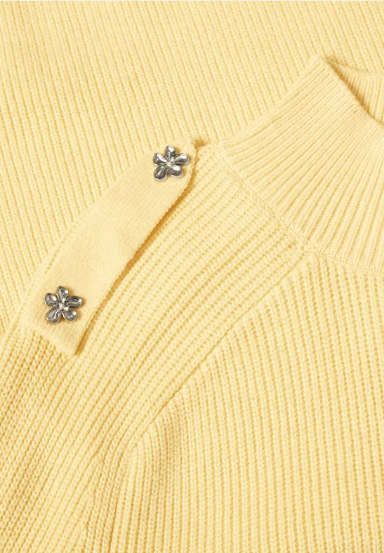 Gelber, gerippter Pullover mit eleganten silbernen Blumenknöpfen.