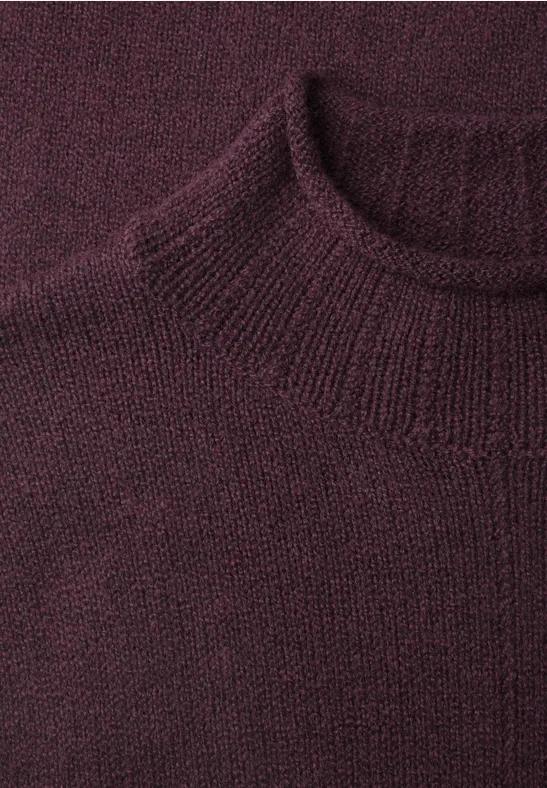 Nahaufnahme eines weinroten, fein gestrickten Pullovers mit geripptem Rundhalsausschnitt.