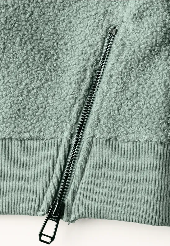 Nahaufnahme eines Reißverschlusses an einem weichen, strukturierten Teddy-Fleece-Stoff.