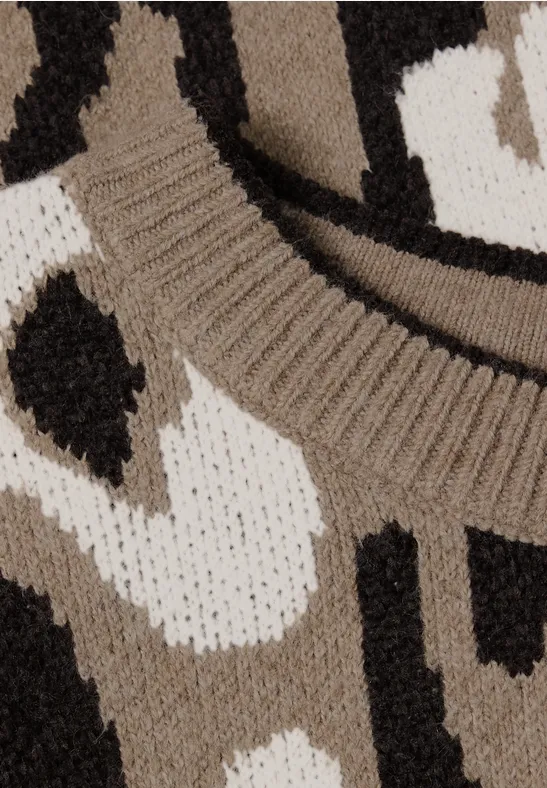 Nahaufnahme eines mehrfarbigen, gemusterten Strickpullovers in Beige, Weiß und Schwarz.