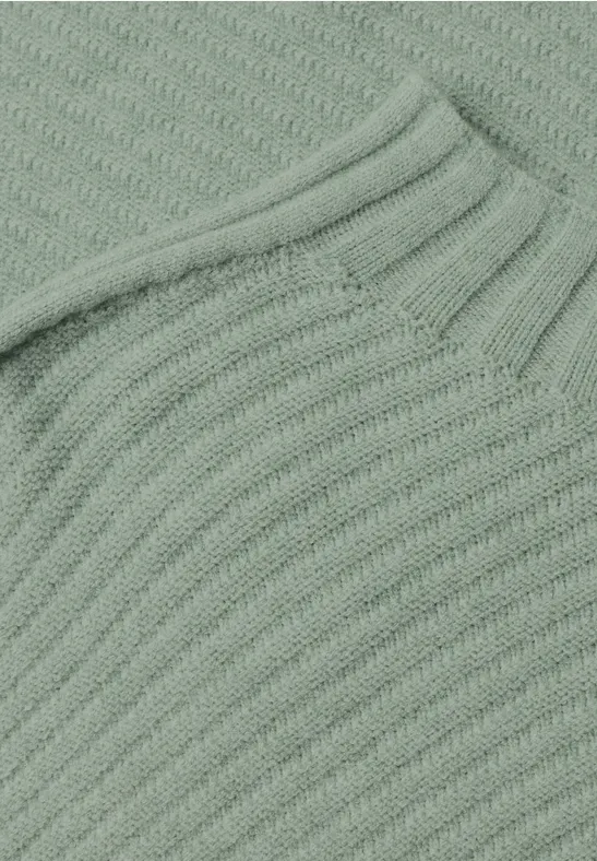 Detail eines hellgrünen, grob gestrickten Pullovers