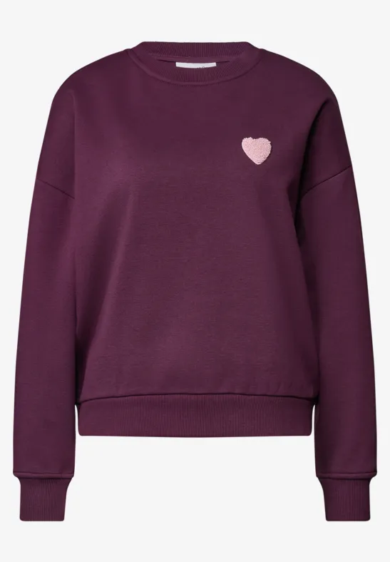 Dunkellila Damenpullover mit langen Ärmeln, geripptem Saum und kleinem rosa Herz-Logo auf der Brust.