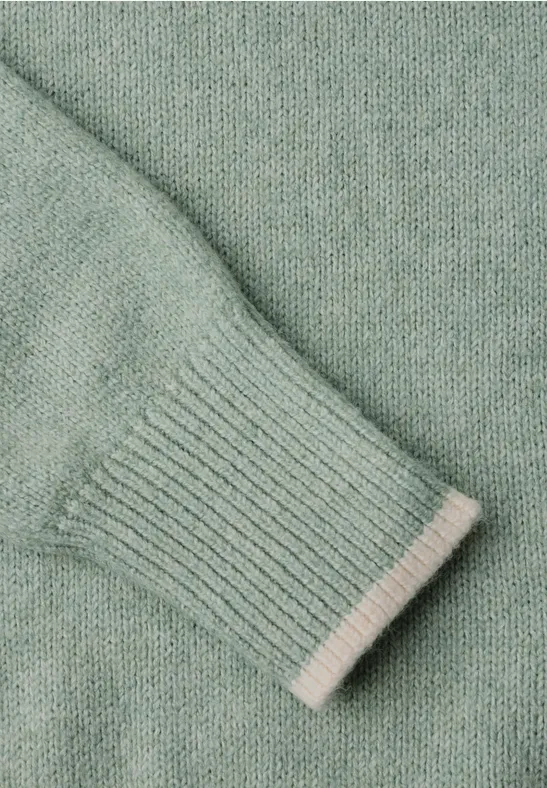 Nahaufnahme eines mintgrünen Strickpullover-Ärmels mit Rippbündchen.