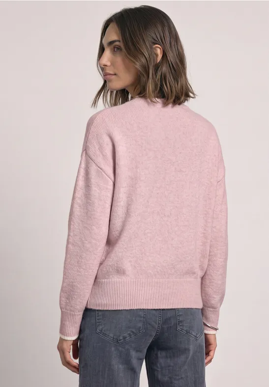 Frau von hinten in rosafarbenem Pullover und dunkler Jeans