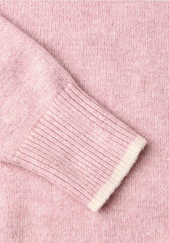Nahaufnahme eines rosa gestrickten Pullovers mit Rippbündchen.
