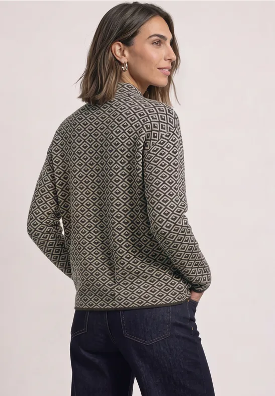 Frau von hinten in einem gemusterten, olivgrünen Pullover mit hohem Kragen und langen Ärmeln.