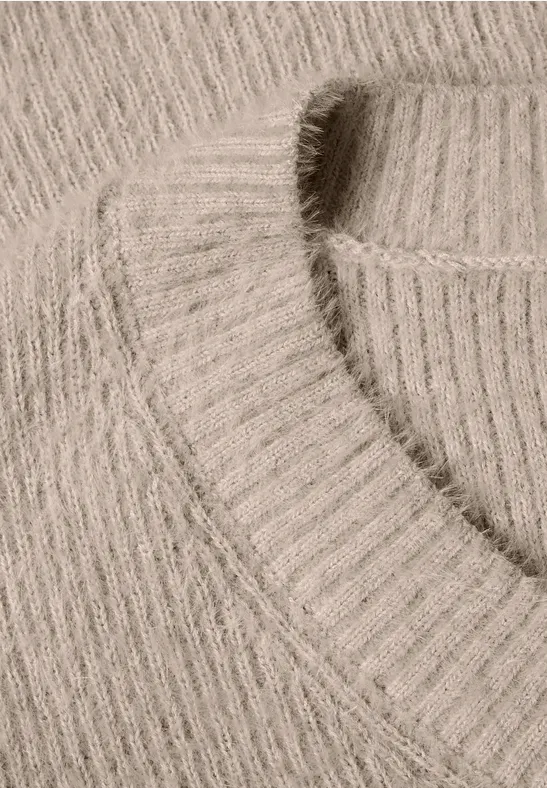 Nahaufnahme eines hellbeigen, gerippten Strickpullovers