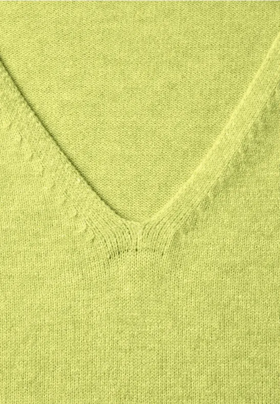 Gros plan d’un col en V en maille vert pastel.