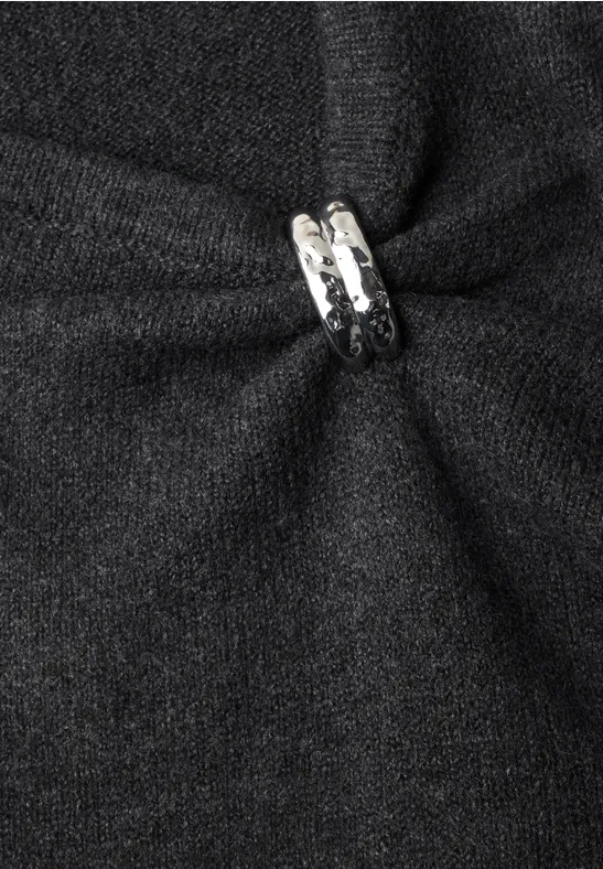Schwarzer Stoff mit einem zentralen Faltenwurf, gehalten von einem silbernen Ring als dekoratives Detail.
