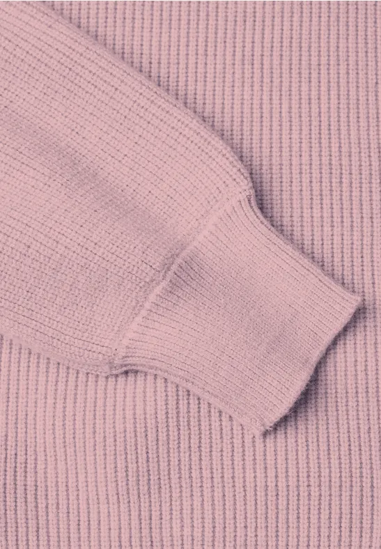 Nahaufnahme eines rosa gerippten Pullovers mit Bündchen am Ärmel.