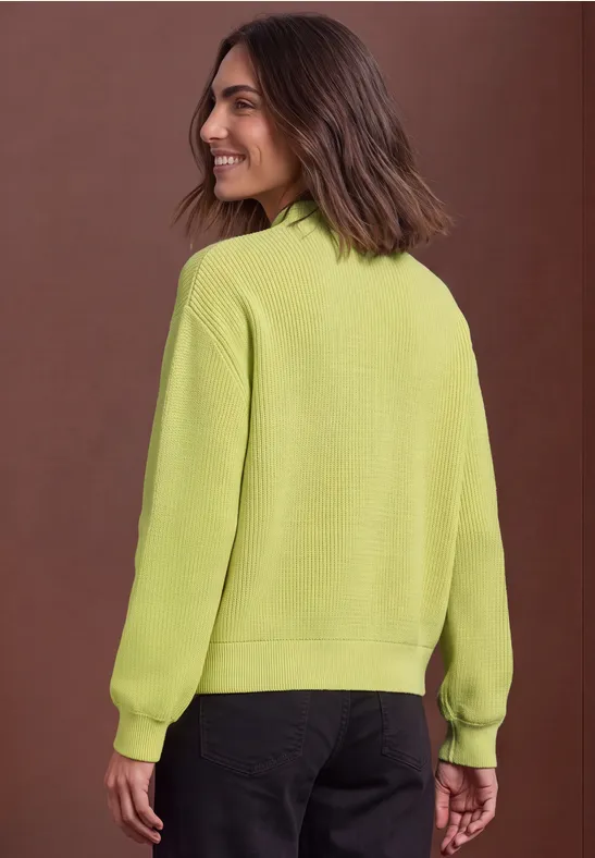 Eine Frau in einem hellgrünen Pullover blickt über die Schulter.