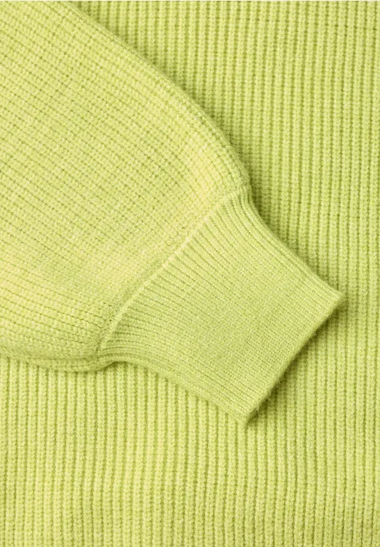 Nahaufnahme eines limettengrünen Strickpullovers mit Rippstrick und Bündchen.