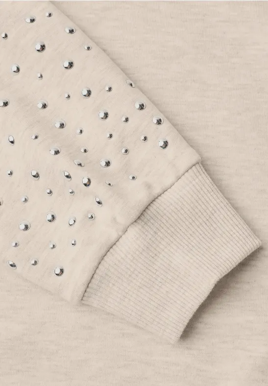 Manche de sweatshirt beige avec bord-côte, ornée de strass brillants.