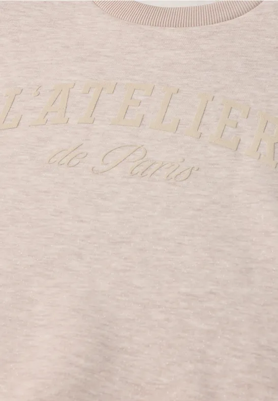 Beige-rosafarbener Pullover mit aufgesticktem Schriftzug 'L'ATELIER de Paris' auf der Brust.