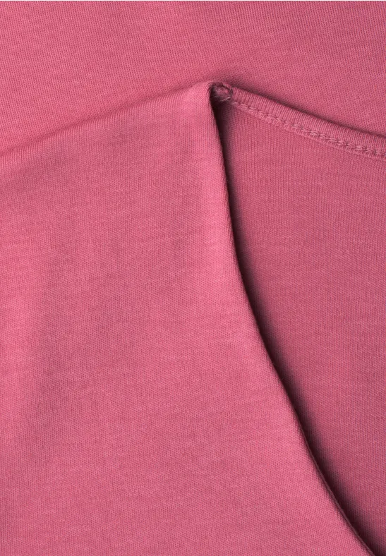 Close-up van een roze kledingstuk met een afgeronde zak en zichtbare naden.