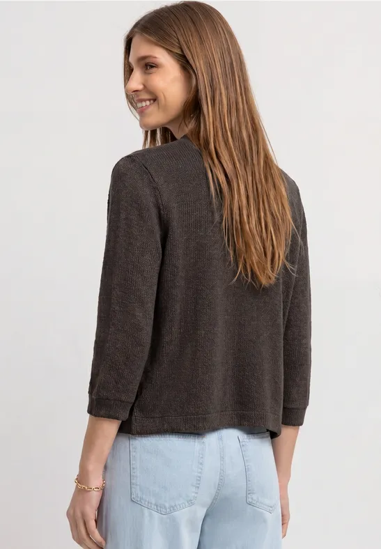 Vrouw van achteren in een bruine jas en lichtblauwe spijkerbroek.