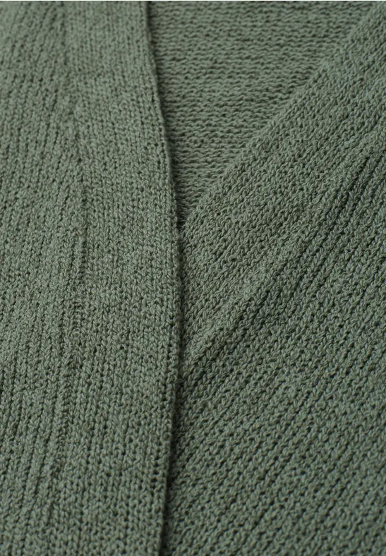 Gros plan sur un tissu tricoté vert à la texture douce et au motif de mailles fines.