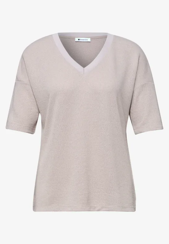 Beige top met V-hals en halflange mouwen.