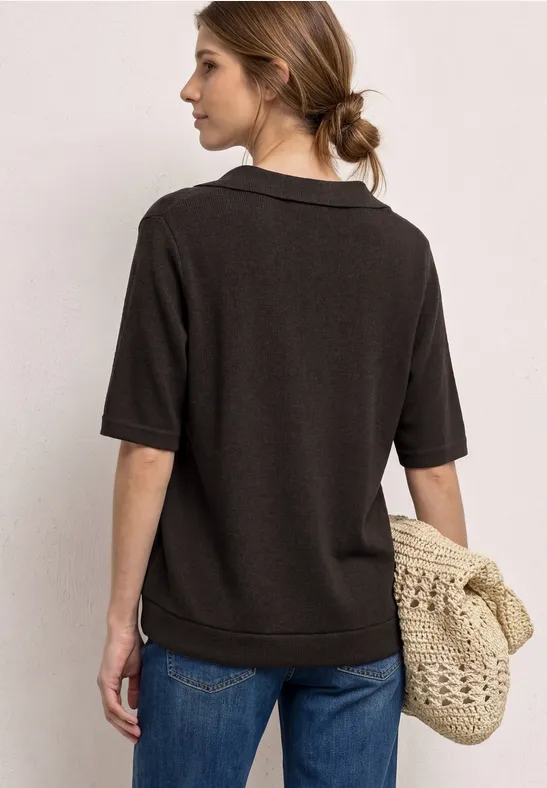 Femme vue de dos portant un polo sombre, un jean et un sac tressé