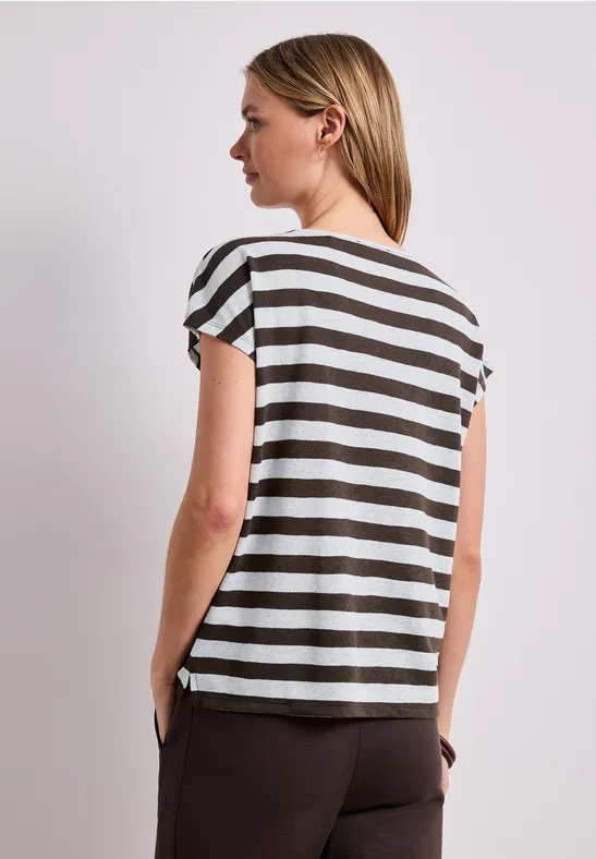 Femme vue de dos portant un t-shirt à rayures et un pantalon marron.