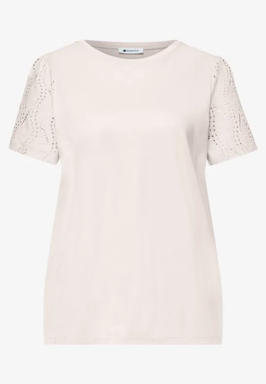 Ein schlichtes cremefarbenes T-Shirt mit kurzen Spitzenärmeln.