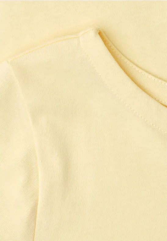 Close-up van een lichtgeel T-shirt met ronde hals.