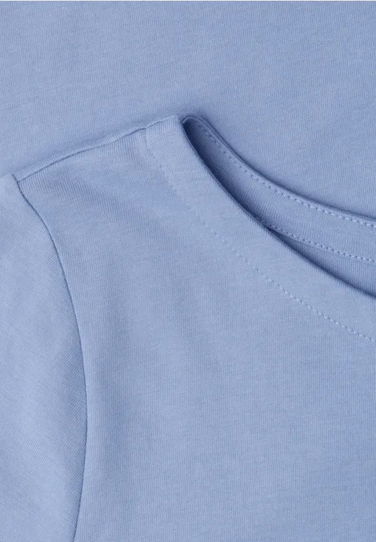 Close-up van een lichtblauw T-shirt met ronde hals en schouderstuk
