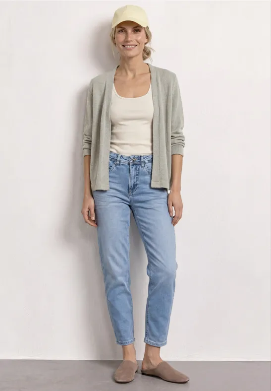 Femme en cardigan gris clair, débardeur blanc, jean bleu taille haute et mocassins marron.