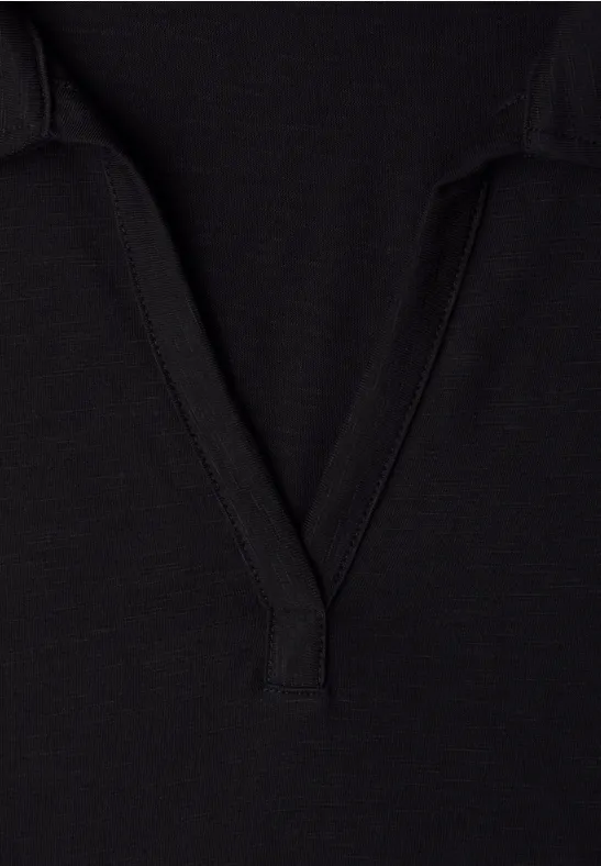 Zwart getextureerd stofdetail met V-hals, vermoedelijk onderdeel van een T-shirt of polo.