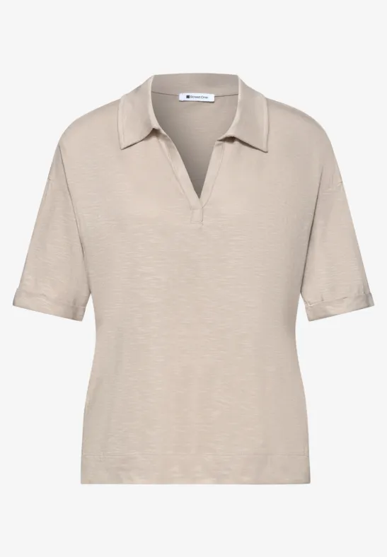 Beige damespolo met korte mouwen, V-hals en een losse pasvorm.