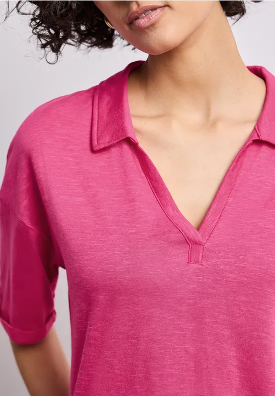 Vrouw draagt losse roze V-hals top met kraag en halflange mouwen