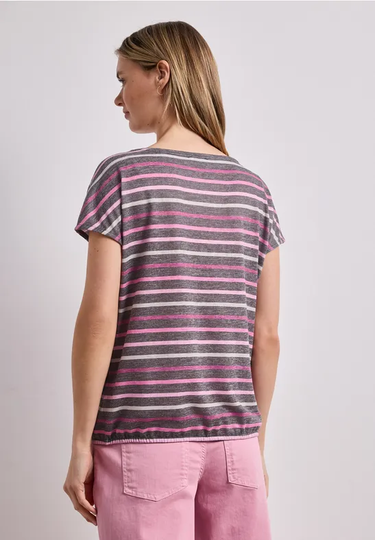 Frau von hinten in gestreiftem T-Shirt und rosa Hose vor weißem Hintergrund.