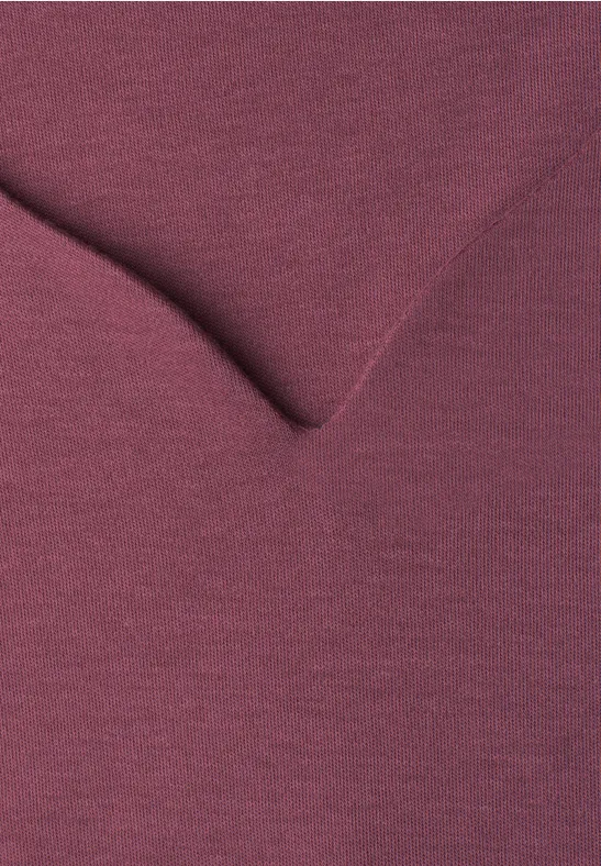 Close-up van een bordeauxkleurig V-hals kledingstuk met fijne structuur.
