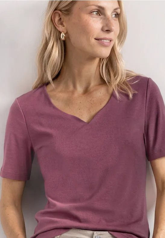 Een vrouw draagt een paars T-shirt met korte mouwen en V-hals, close-up van het bovenlichaam.