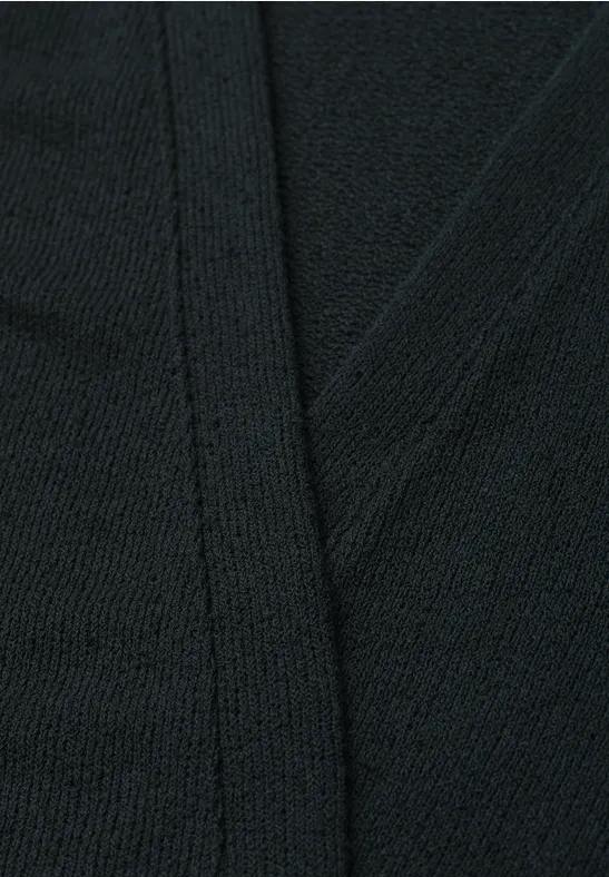 Gros plan d’un tissu tricoté noir avec couture visible.