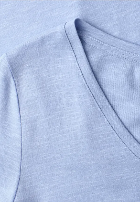 Gros plan sur un t-shirt col V bleu clair à texture subtile