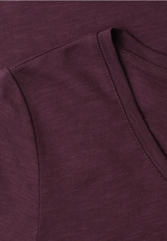 Nahaufnahme eines dunkelroten T-Shirts mit Rundhalsausschnitt und feiner Stoffstruktur.
