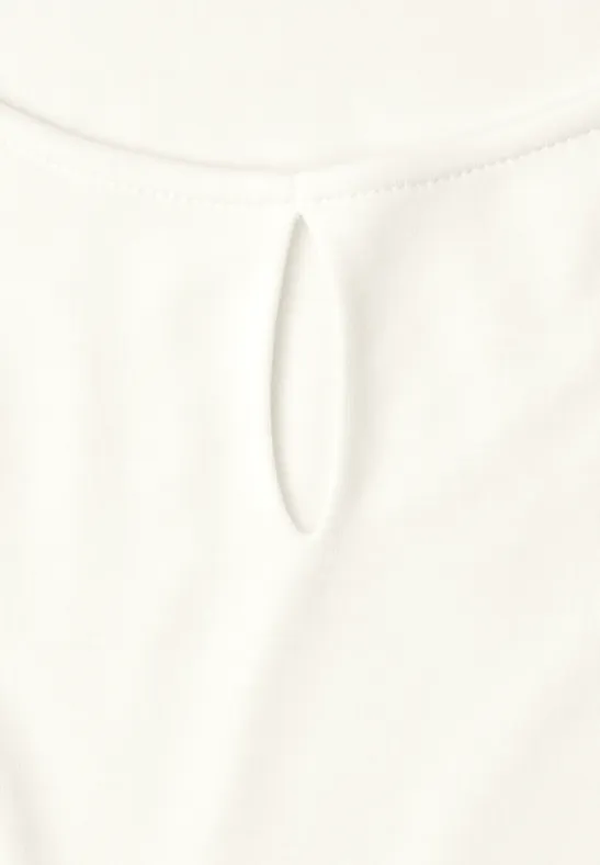 Witte blouse met een kleine ovale uitsparing bij de ronde halslijn.