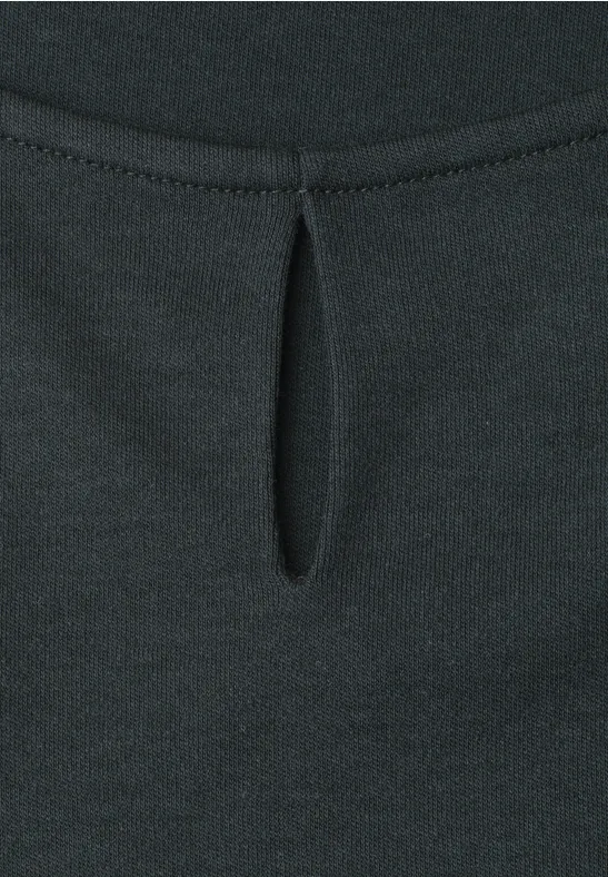 Detailaufnahme eines schwarzen Oberteils mit kleinem tropfenförmigem Ausschnitt und Bügelfalte.