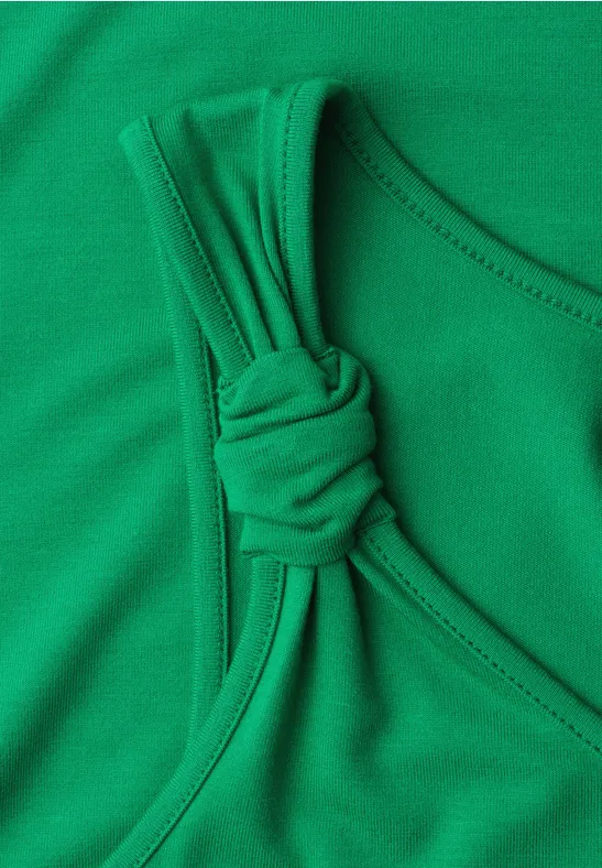 Haut de maillot de bain vert sans manches avec nœud décoratif sur la bretelle.