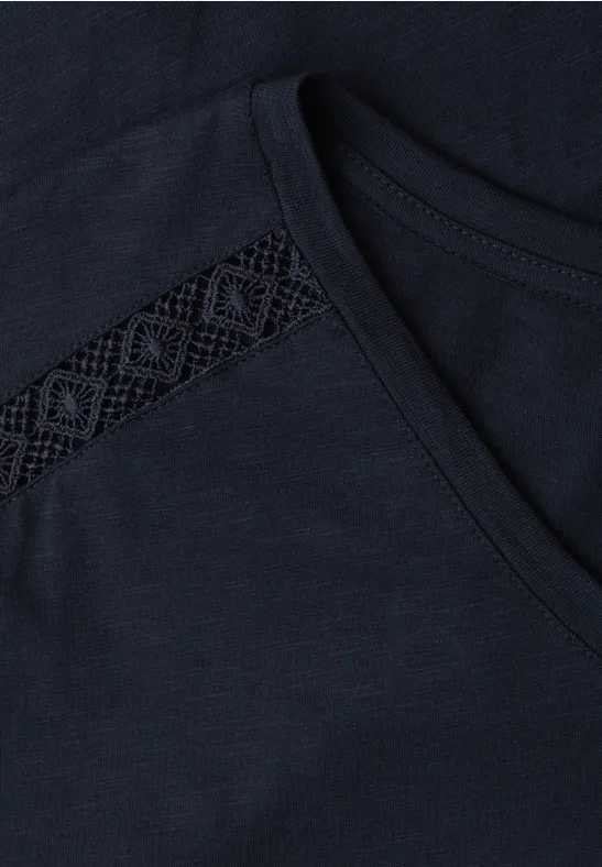 Dunkelblaues T-Shirt mit Brusttasche und filigraner Spitzeneinfassung am Ausschnitt.