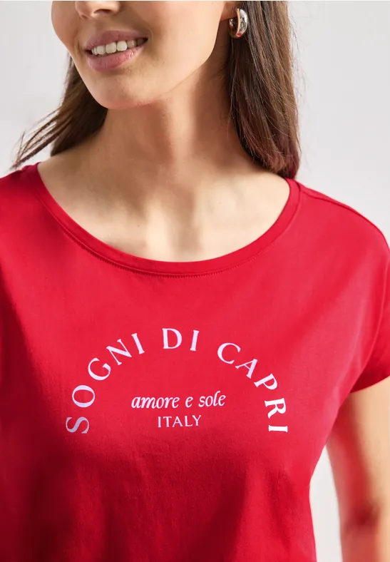 Vrouw in rood T-shirt met witte tekst 'Sogni di Capri amore e sole Italy'.